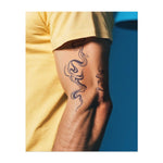 Gekrümmte, sich windende Linien, die fließendem Rauch oder Flüssigkeit ähneln und sich in einem grazilen, organischen Muster bewegen. Das Tattoo symbolisiert Fluidität, Veränderung und Freiheit.